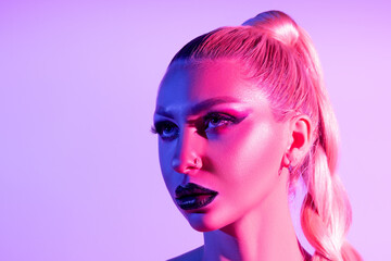 Fashion model woman with a bright make-up in colourful bright neon uv lights posing in studio.