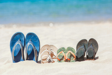 A Slippers of the whole family in the sand by the sea on nature while traveling. Rest by the water...