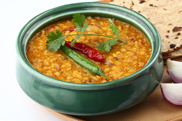 Indian popular food Dal Tadka Curry served with roti flatbread close-up on the table. Vertical top...