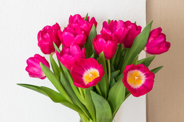 bouquet of bright pink fuchsia tulips in a glass vase on a wooden table	
