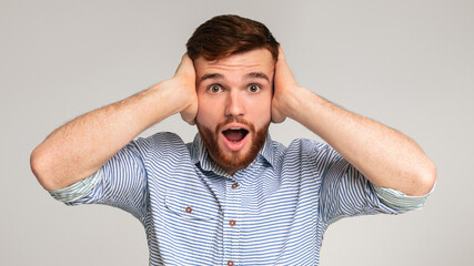 Angry with nosy neighbors. Portrait of irritated man shouting and covering his ears on studio...