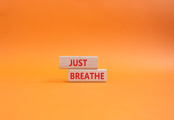 Just Breathe symbol. Wooden blocks with words Just Breathe. Beautiful orange background. Business...