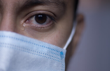 look photograph of a person with a tear under his eye wearing a face mask
