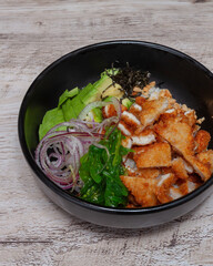 Chicken and seaweed poke in a black bowl on wooden table