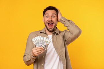 A man is seen holding money in his hand while making a comical expression on his face. His eyes are...
