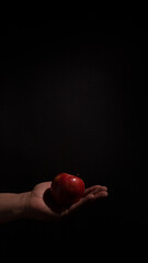 apple held by one hand on black background