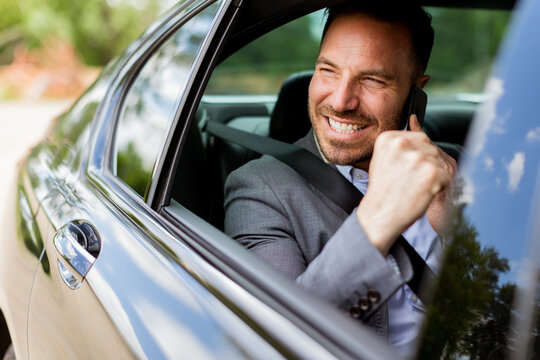Joyful man sharing laughter on a phone call while driving in daylight