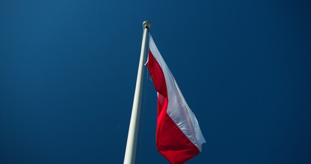 Polish flag on the mast l blue sky at the background 