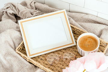 Still life photo frame mockup, coffee cup, pink flowers in wicker tray. Top view.