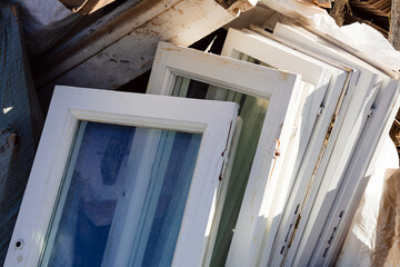Construction waste for disposal. Heap of old wooden window frames with glass outdoors. Renovation and reconstruction concept. Replacement of windows in building. Bulky waste collection.