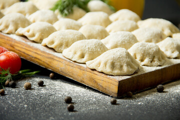dumplings on a cutting board. raw dumplings on a black background.