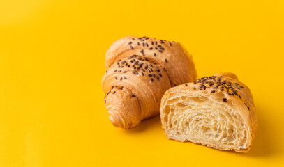Macro shot of fresh croissant cut in a half on the yellow background. Copy space for a free text