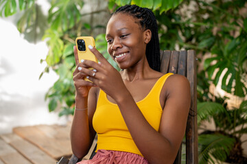 Cheerful african girl with smartphone. Smiling joyful black African American woman using phone...