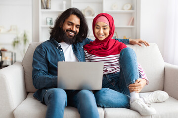 Bright and airy shot of a young eastern couple using a laptop together, showcasing a moment of...