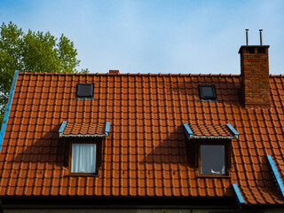 roof of a house made of red tiles with a chimney and attic