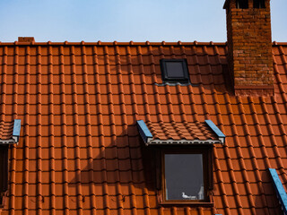 roof of a house made of red tiles with a chimney and attic
