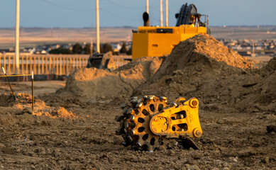 Close view of compaction wheel excavator attachment in the construction site at sunset