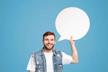 Millennial guy having idea. Smiling young man holding blank speech bubble and looking at camera on...