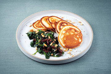 Traditional American pancakes with spinach, pine-nuts and raisins served as close-up on a Nordic...