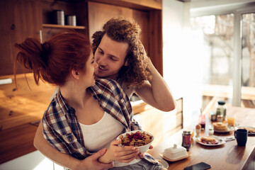 Happy couple embracing and kissing in sunny kitchen