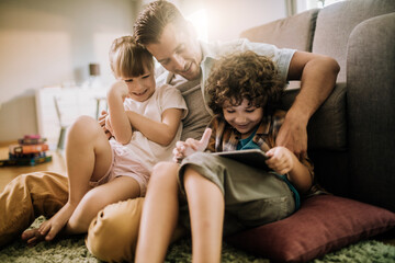 Happy father playing with son and daughter at home