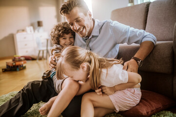 Happy father playing with son and daughter at home