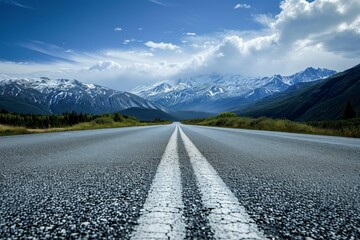 Low angle view of a road leading straight to majestic mountains under a blue sky