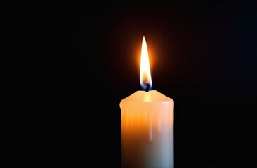 Candle burns on a dark black background, close-up