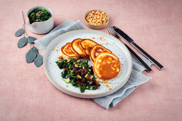 Traditional American pancakes with spinach, pine-nuts and raisins served as close-up on a Nordic...