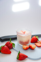 A homemade natural yogurt with fresh red strawberries on a cutting board and a knife