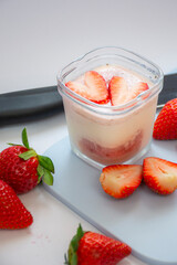 A homemade natural yogurt with fresh red strawberries on a cutting board and a knife