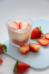 A homemade natural yogurt with fresh red strawberries on a cutting board