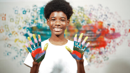 African boy looking at camera while showing two side of hand to camera with colorful color. Smiling...