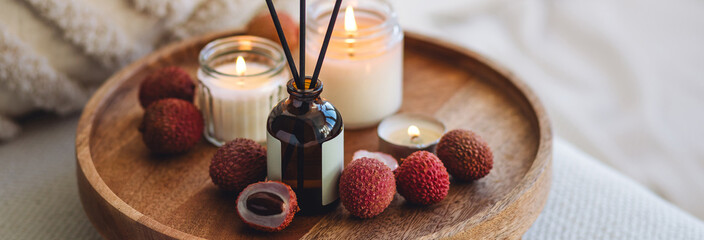 Banner. Aromatherapy, relaxation, detention. Burning candles on wooden bamboo tray. Fruity litchee aroma reed home diffuser on wooden table. Atmosphere of calm, meditation, Bali and Thai interior
