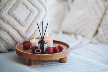 Sweet home perfume with tropical exotic fruits. Reed diffuser on wooden tray in a bedroom. Burning...
