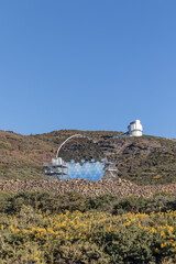 Astronomical observatory with telescopes and the moon in the sky, a large mirror is also visible.
