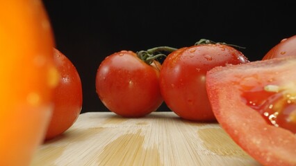 Macrography, slices of tomato rest elegantly on a rustic cutting board against a dramatic black...