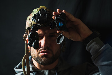 Portrait of a military man with a beard with a binocular night vision device on his head. Soft...