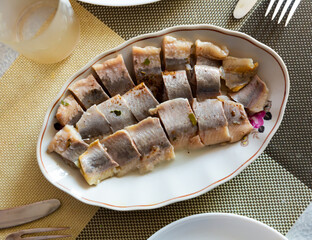 Freshly salted pickled herring fish served on a ceramic plate in a cafe