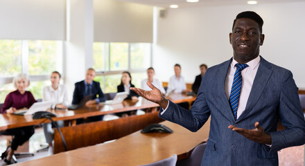 Portrait of confident african-american businessman in suit standing in meeting room, making...