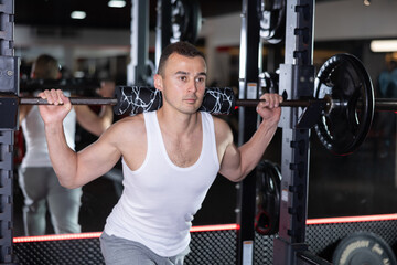 Sporty man performing set of exercises with barbell during intense workout. Concept of weight...