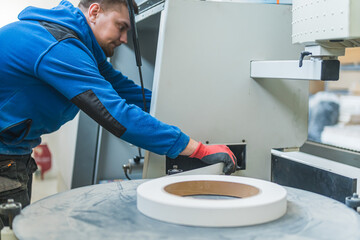 carpenter taking tape out of a machine at the workshop, manufacture concept. High quality photo