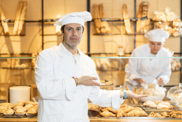 Confident male baker welcoming everyone into his bakery