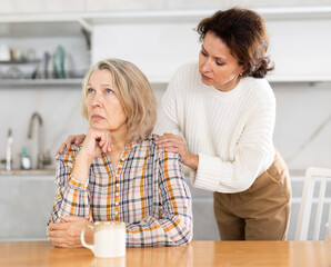 Adult daughter apologizes to her elderly mother after a domestic quarrel.