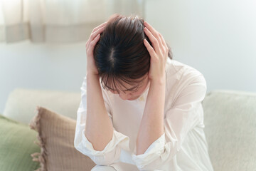 頭を抱える女性　頭痛　体調不良