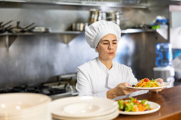 Female chef puts ready meals on shelves in restaurant