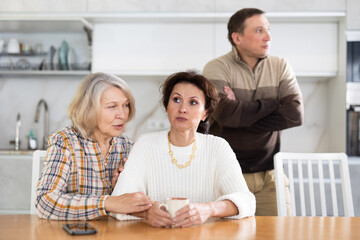 Family quarrel, old woman calming woman, all are upset and dissatisfied