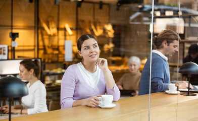 Portrait of young attractive girl drinking coffee in modern cafe