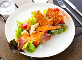 Traditional French Basque salad with sliced smoked duck breast, sheep cheese, fresh lettuce leaves,...