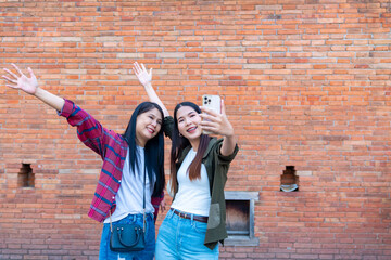 Asian woman friends using smartphone taking selfie or vlogging during travel together in Chiang Mai...